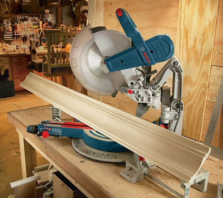A close-up application shot of the Bosch PRO1280FIN blade in a miter saw setup, perfectly aligned to cut decorative crown molding with a smooth, professional finish that requires minimal sanding.