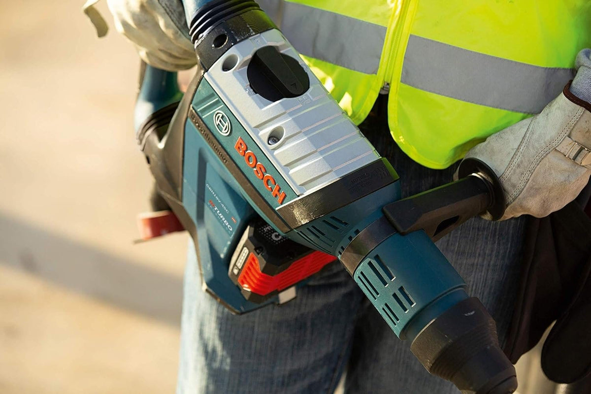 Close-up view of a worker's hands holding the Bosch GBH18V-45CK24 PROFACTOR 18V Hitman rotary hammer, highlighting the top-mounted Vario-Lock mode selector dial and heavy-duty tool construction.