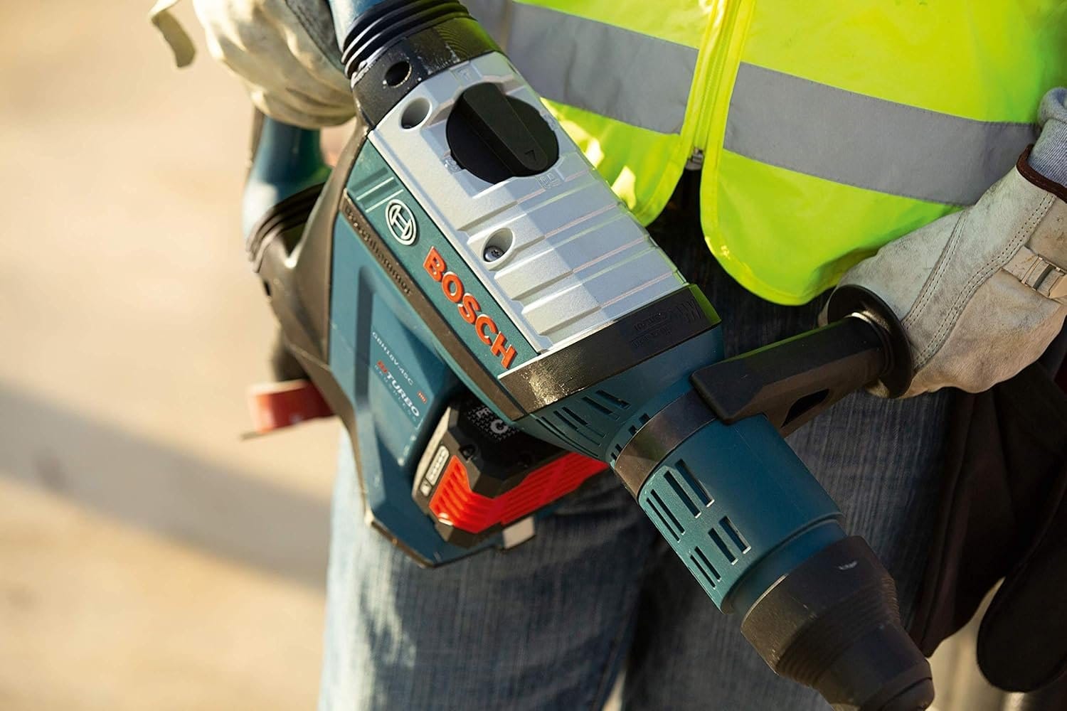 Close-up view of a worker's hands holding the Bosch GBH18V-45CK24 PROFACTOR 18V Hitman rotary hammer, highlighting the top-mounted Vario-Lock mode selector dial and heavy-duty tool construction.