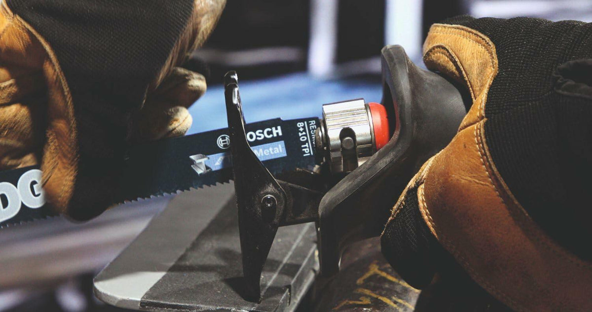 Worker inserting Bosch S 123 XF bi-metal blade labeled “Metal” into reciprocating saw using quick-release mechanism. Gloved hands emphasize safe handling and tool setup for metal cutting.