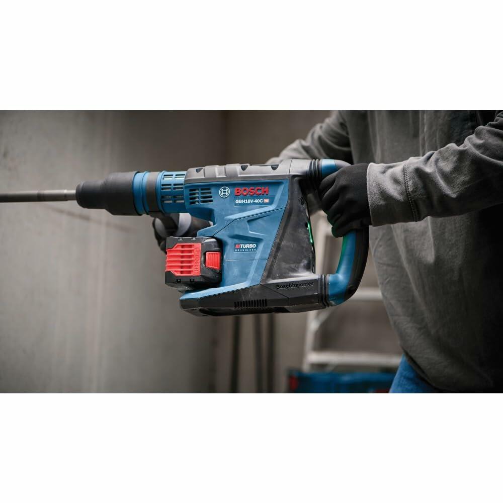 Bosch GBH18V-45C rotary hammer drill used horizontally on masonry surface. Tool features BITURBO Brushless label. Worker wears gloves and long sleeves in industrial setting.