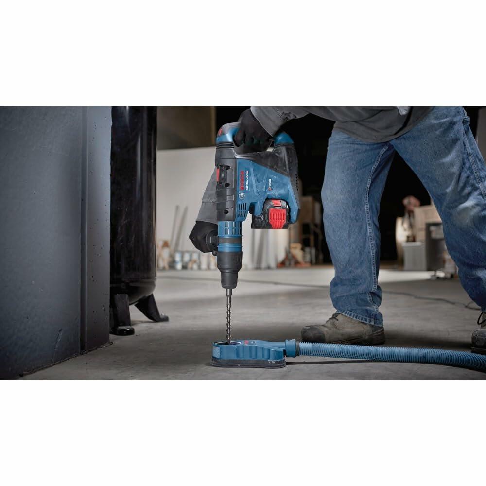 Worker using Bosch cordless rotary hammer drill on a concrete surface. Tool features visible battery pack and accessory attachment. Scene highlights professional-grade drilling in construction setting.