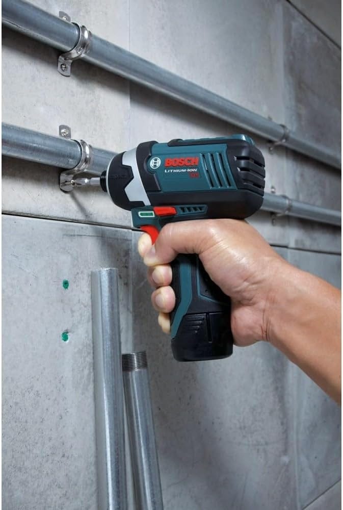 A close-up of a person using the Bosch PS41-2A impact driver to fasten a metal conduit clamp onto a concrete wall.