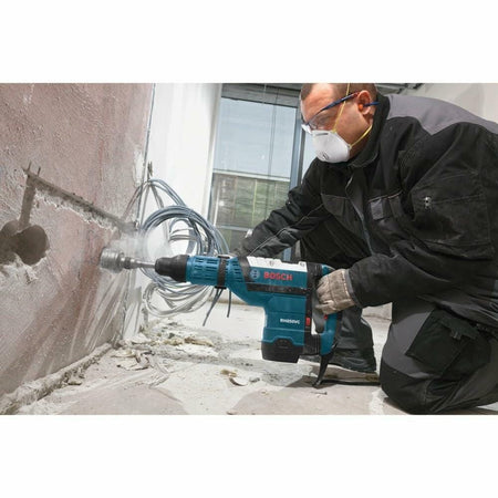 A worker uses the Bosch RH850VC hammer with a large core bit to drill horizontally through a concrete wall.
