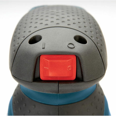 A macro close-up view of the front of the sander head cap, focusing on the mechanical red power rock toggle switch with raised international binary icons representing on and off selections.