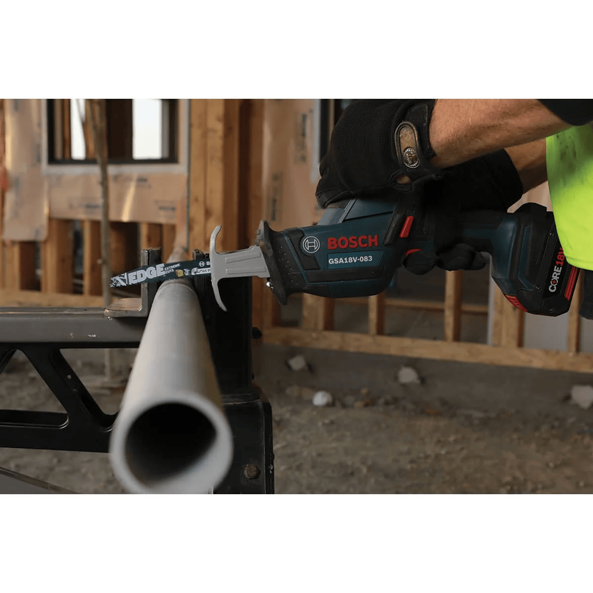 Worker using a Bosch 18V cordless reciprocating saw equipped with an Edge 6-inch bi-metal blade cutting smoothly through heavy-duty pipe clamped to a work stand.