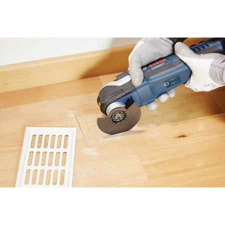 Action shot of the blade cutting a rectangular opening in laminate flooring for a vent installation.
