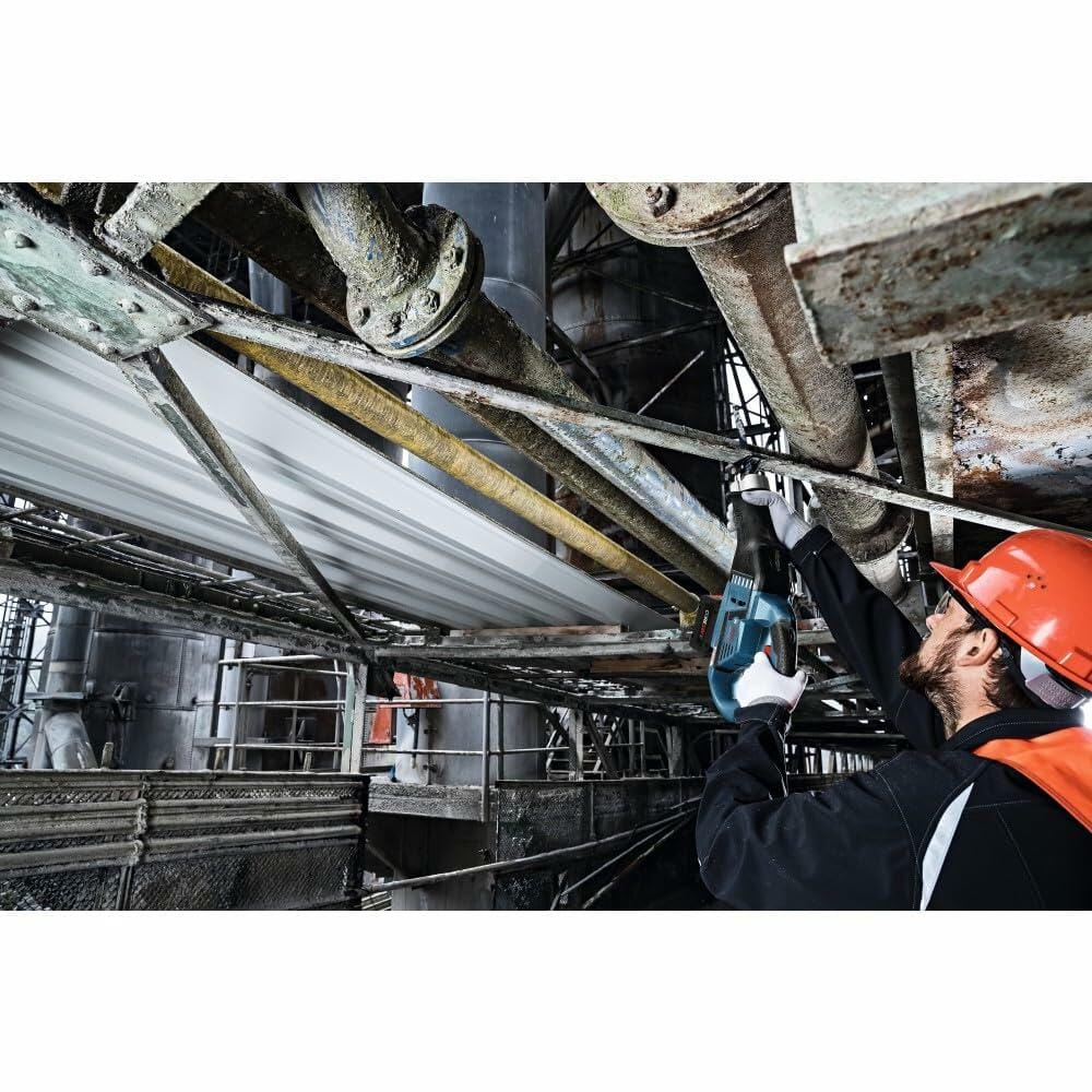 Worker in a red safety helmet using a Bosch reciprocating saw or impact tool on a large metal pipe in an industrial setting. The image highlights the tool’s utility in heavy-duty maintenance or construction environments.