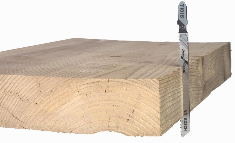 A side-view action shot of a Bosch T101B Clean for Wood jigsaw blade cutting through a thick piece of lumber, demonstrating the depth and precision of the cut.