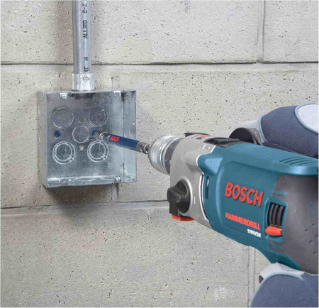Close-up of a worker using a Bosch hammer drill equipped with a masonry bit to precisely drill a hole through a metal electrical box mounted on a concrete block wall.