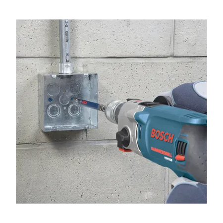 A close-up application shot of an industrial mechanic using a corded Bosch hammer drill to fasten a masonry screw inside a metallic electrical junction box mounted to a concrete block wall. The tool is equipped with the extended steel drive sleeve from the TCHC9 installation kit to drive the fastener securely into a pre-drilled pilot hole.