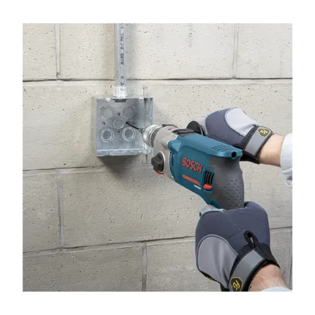An action application shot displaying the preliminary phase of masonry anchoring where a technician uses a corded Bosch hammer drill tool to bore a precision pilot hole into a concrete block background. The user guides the specialized masonry bit from the TCHC9 kit directly into marked guidelines on the wall to ensure a perfectly clean and straight anchoring socket.