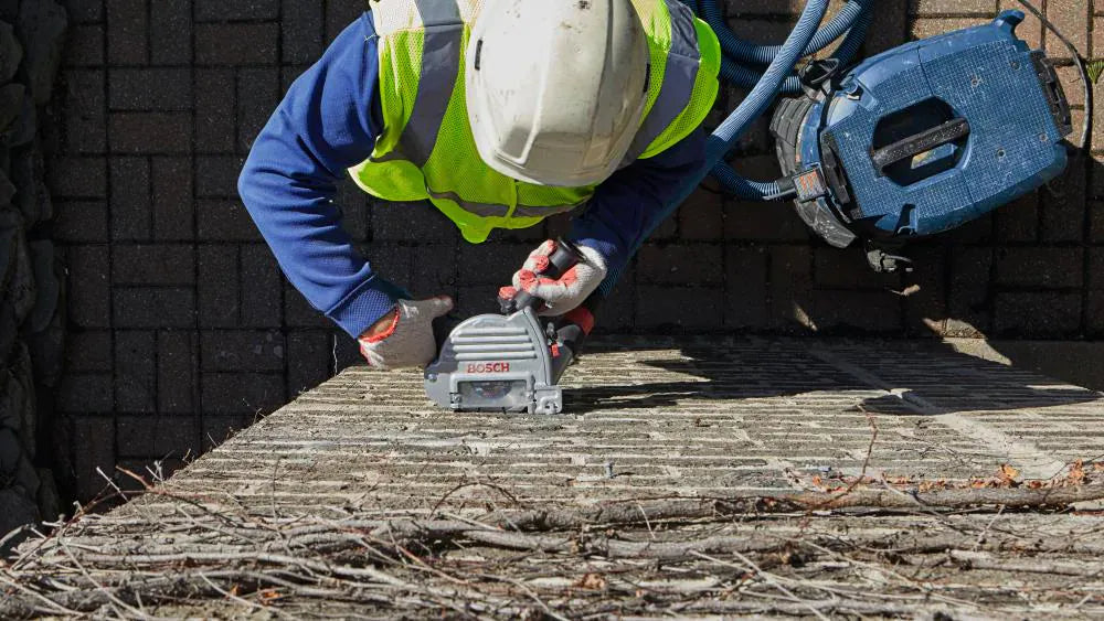 An overhead view of a masonry professional using the Bosch TG502 guard, highlighting the clear line of sight through the viewing window while grinding horizontal mortar joints.