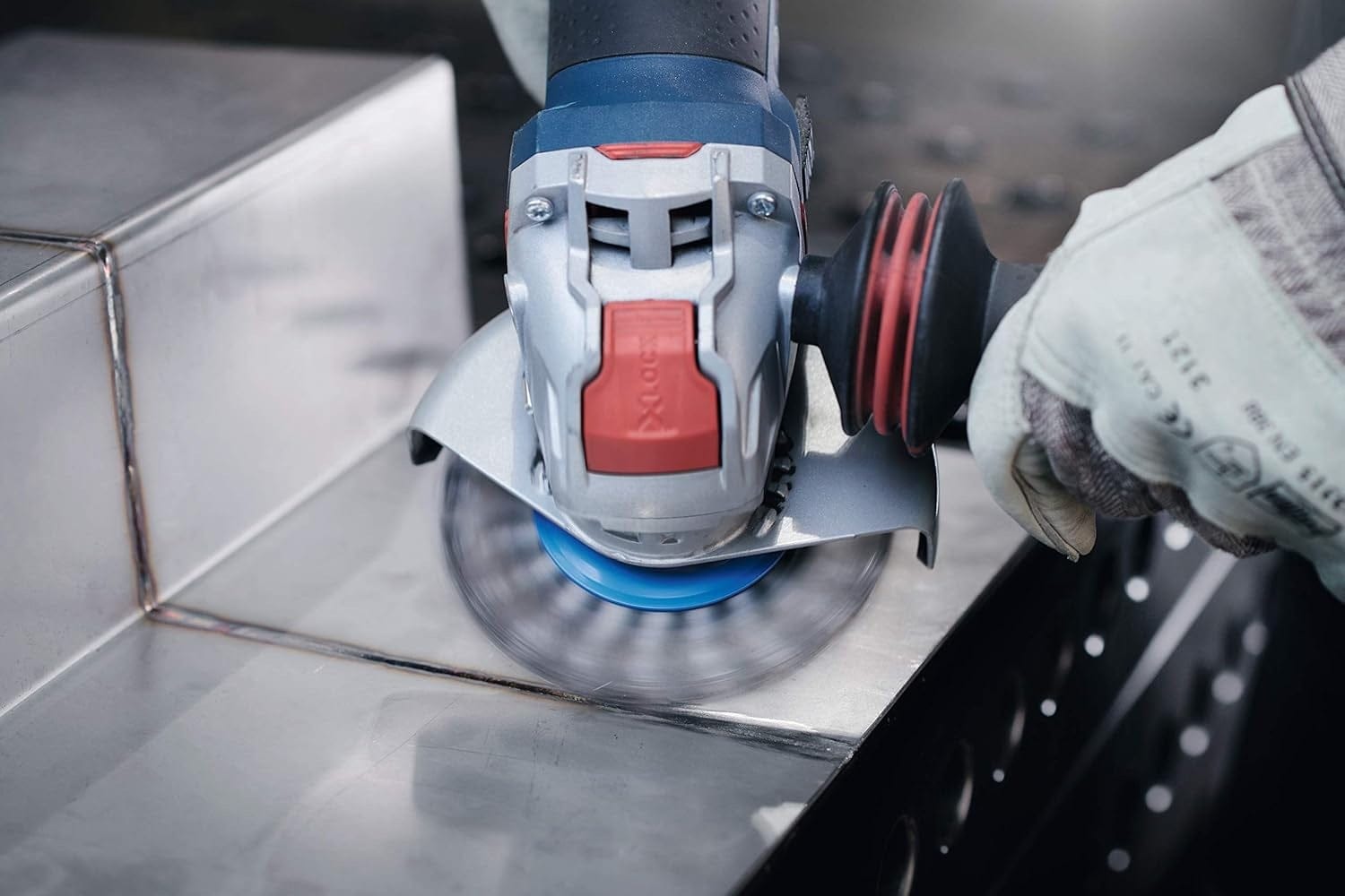 Action shot of the wire wheel spinning on an angle grinder cleaning a corner weld on a stainless steel piece.