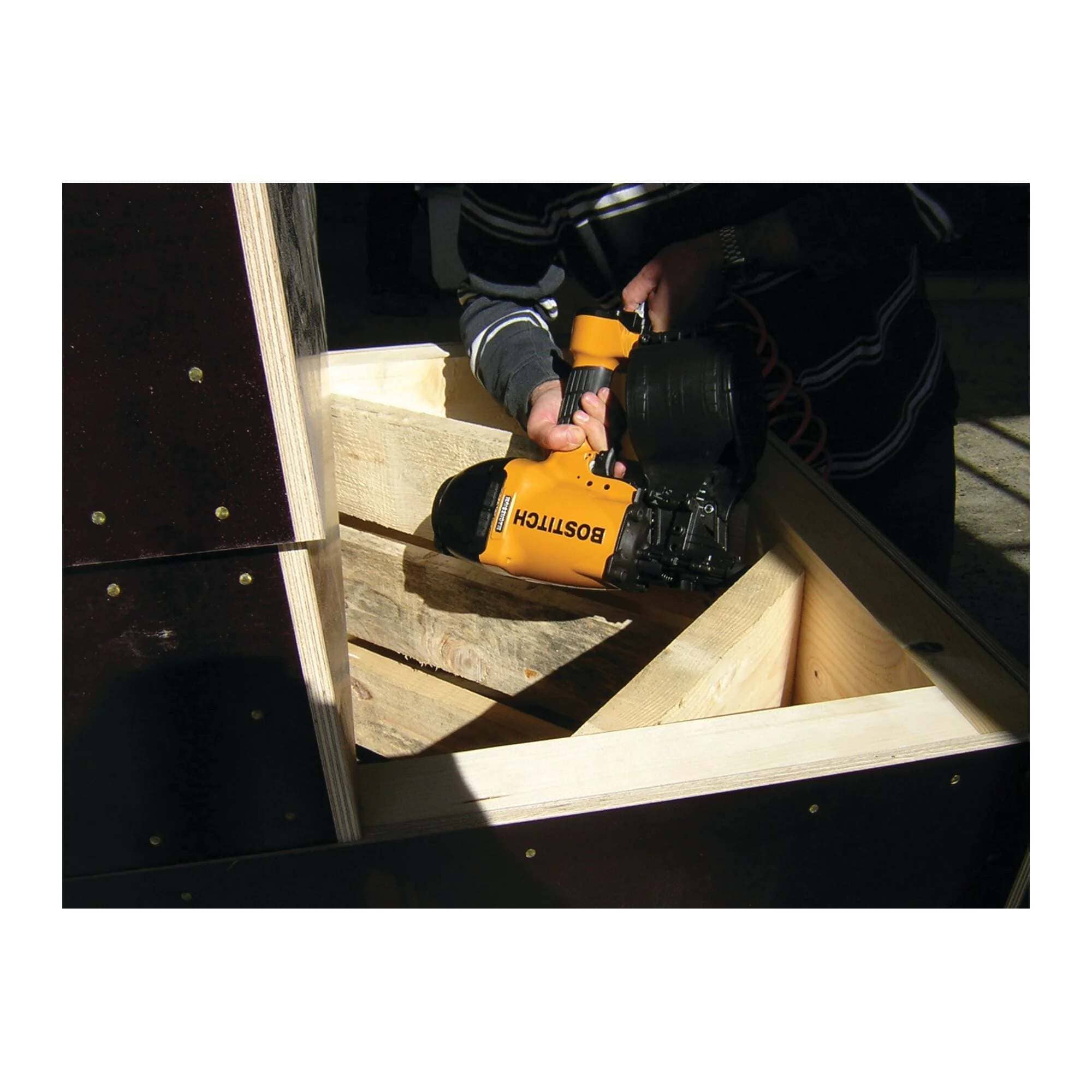 Action shot of a professional using the Bostitch N89C-1 pneumatic nail gun for high-production assembly, demonstrating the tool's compact design and precision in framing and industrial crating applications.