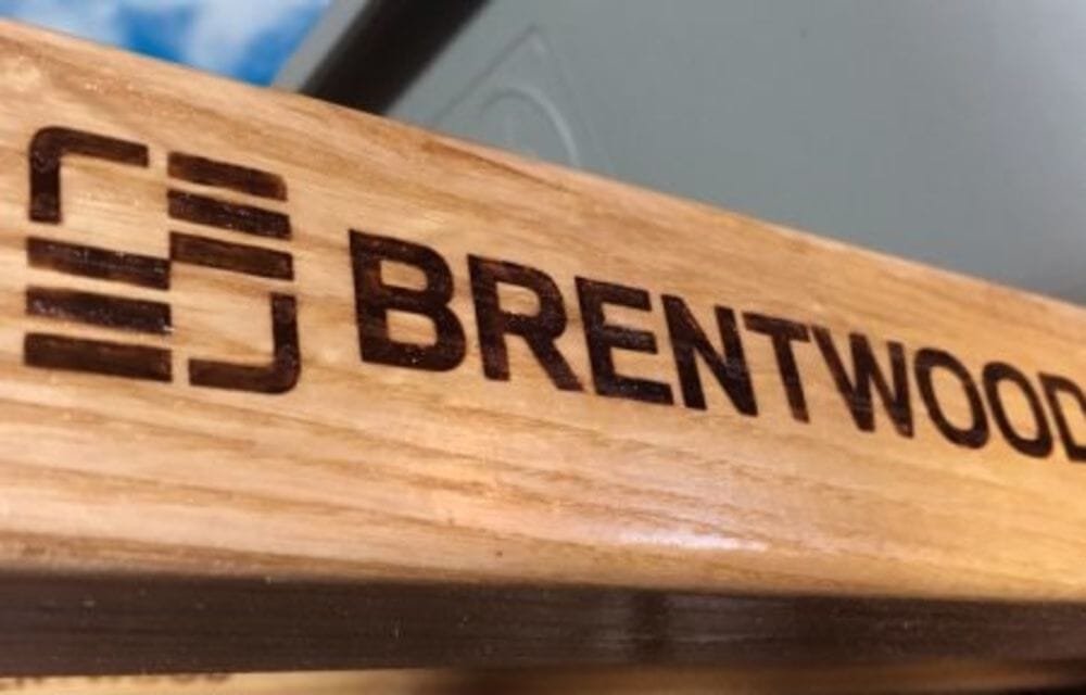 Close-up of the branded North American hardwood handle on the Brentwood wheelbarrow showcasing its durable varnished wood grain.