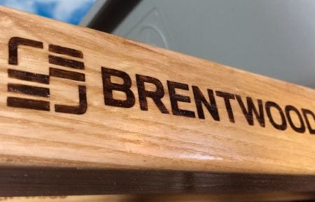 Close-up of the branded North American hardwood handle on the Brentwood wheelbarrow showcasing its durable varnished wood grain.