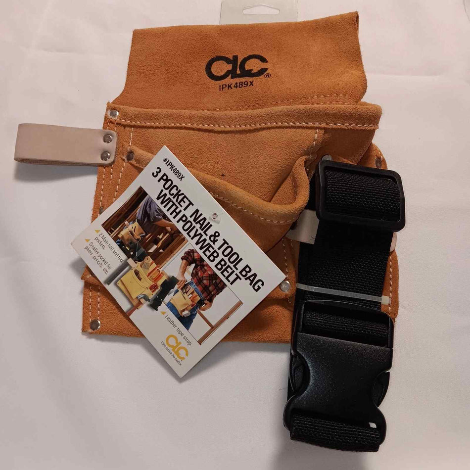 A top-down photograph of a tan suede leather tool bag with three pockets, featuring a black poly web belt with a large plastic quick-release buckle and an attached product information card.