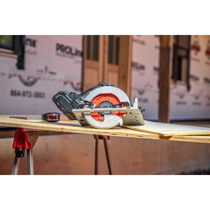 A cordless circular saw equipped with the Crescent 10-inch fiber cement blade resting on a piece of plywood on a sawhorse at a construction site.