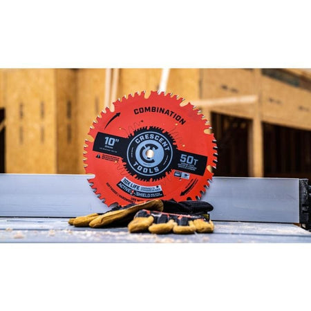 A 10-inch Crescent combination saw blade and work gloves resting on the table of a table saw at a construction site.