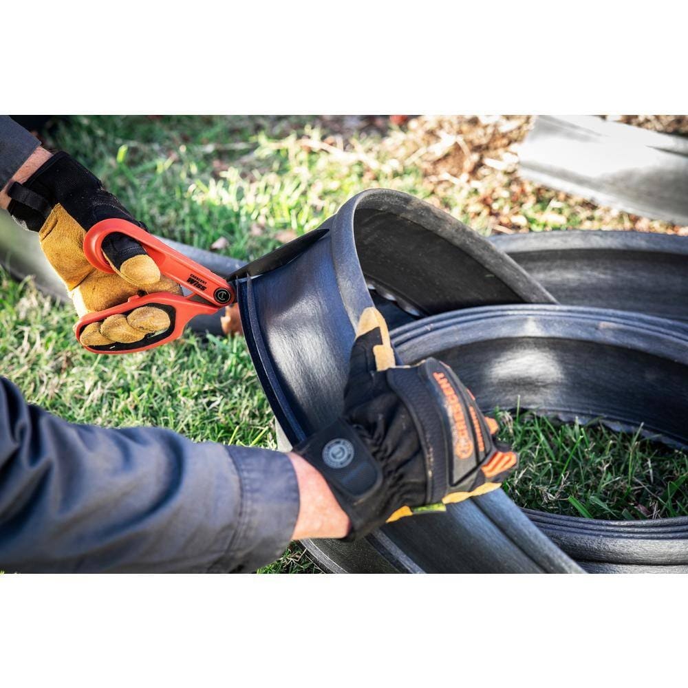 A tradesman wearing safety gloves using the CW10TL left-handed shears to trim thick plastic edging, demonstrating industrial cutting power.