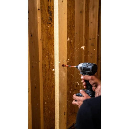 Action shot of a cordless impact driver using a Crescent screw point spade bit to drill a hole through a vertical wooden stud in a framing environment.