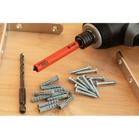 Close-up layout of the Crescent drywall installation set on a wooden surface, showcasing the specialized orange u-GUARD Phillips bit attached to an impact driver alongside the included anchors and drill bit.