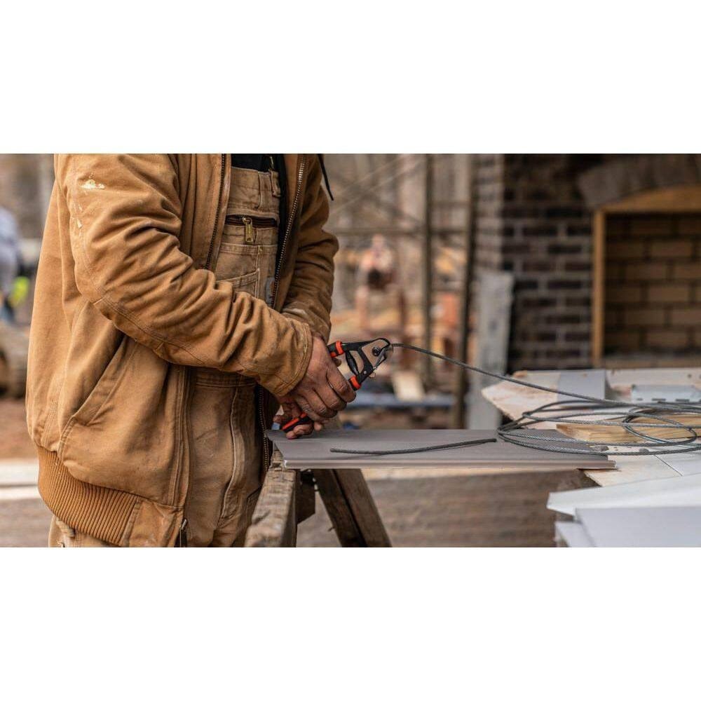 A tradesman using the Crescent 7-1/2 inch pocket wire rope cutter to clip a cable, illustrating the one-handed operation and high-leverage compound action.