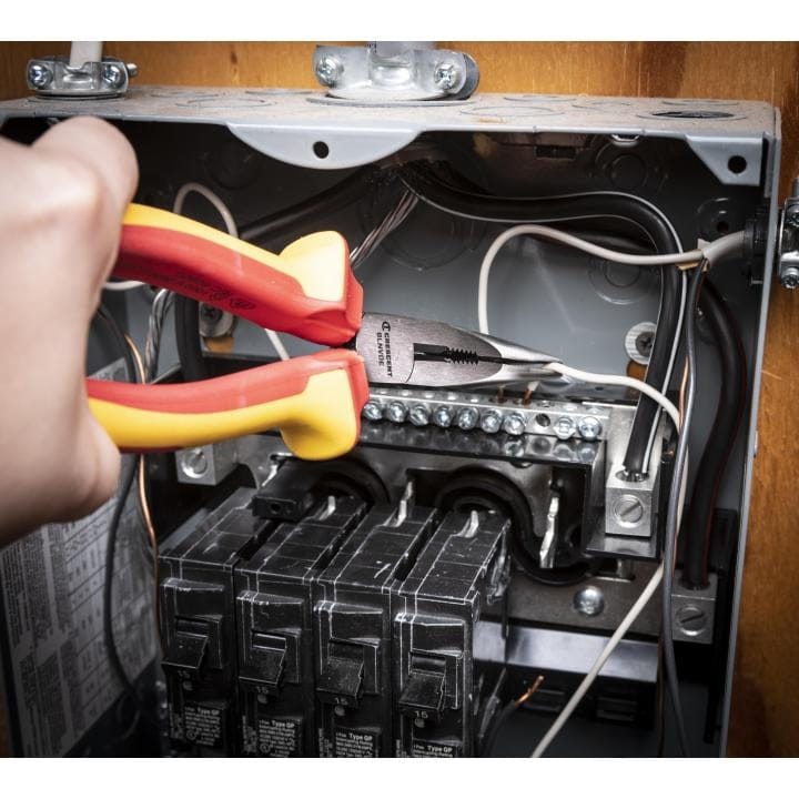 Action shot showing an electrician using the VDE insulated long nose pliers to manipulate electrical wiring inside an open breaker panel