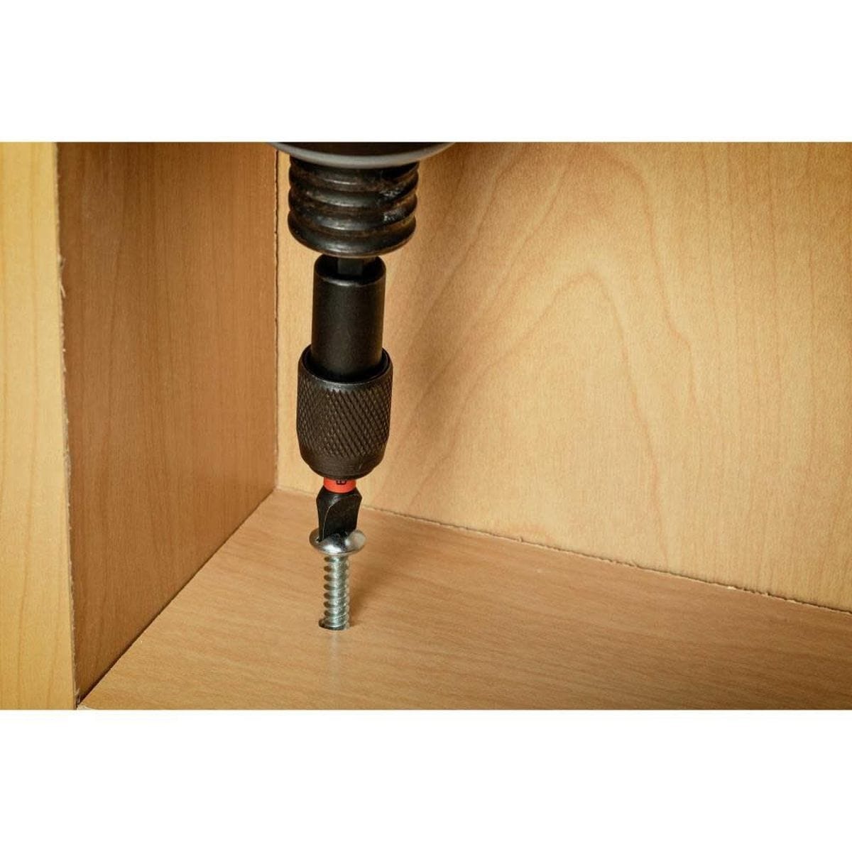 The Crescent APEX slotted impact power bit in use with a cordless impact driver, demonstrating the precise tip fitment as it drives a slotted screw into a wooden cabinetry surface.