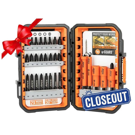 Open Crescent APEX 30-piece fastening bit set displayed in a black and orange alphaCASE storage box. The left side shows rows of labeled bits including Phillips, Torx, and slotted types, with a label reading "2X MORE DURABLE - 50% BETTER GRIP." The right side features orange u-GUARD non-marring sleeves over magnetic nutsetters and bits, with a promotional card highlighting protection benefits. A red ribbon in the corner suggests the set is gift-ready.