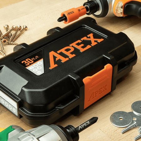 Closed Crescent APEX alphaCASE tool box labeled "30 PC./P." resting on a wooden surface surrounded by screws, washers, and drill bits. Two power tools with APEX bits are nearby, indicating compatibility. The rugged case design and branding emphasize durability and organization for impact-rated fastening tasks.