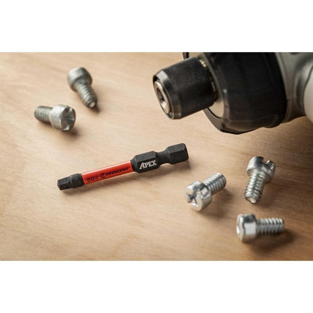Lifestyle shot of the #3 square impact bit resting on a wooden surface next to screws and an impact driver chuck.