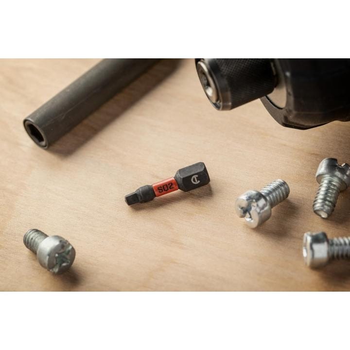 Lifestyle shot of the #2 square impact bit resting on a wooden surface next to screws and an impact driver.