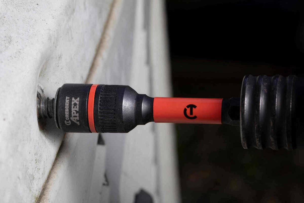 Close-up action shot demonstrating the Crescent APEX Bolt Biter impact nut extractor securely gripping a severely rusted and rounded bolt on a metal surface for easy, slip-free removal.