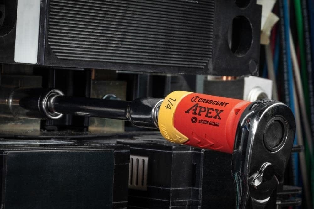 Close-up action shot of the eSHOK-GUARD socket isolator attached to a chrome ratchet, being used to work on a component within an electrical panel.