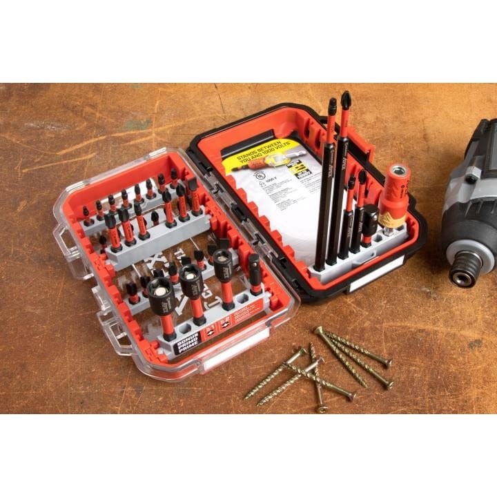 A jobsite application shot of the open Crescent Apex CAESET-40 bit set on a wooden workbench next to high-torque deck screws and an impact driver, demonstrating the set's durability in professional environments.