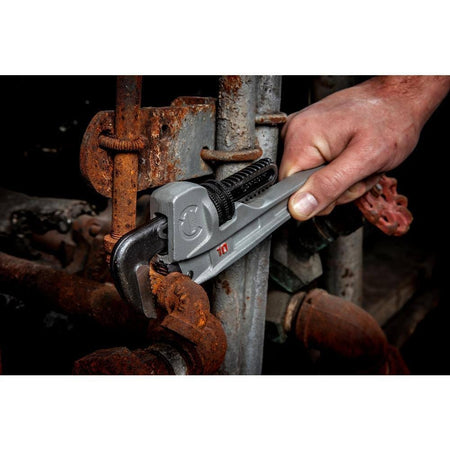 A plumber's hand using the Crescent CAPW10S aluminum pipe wrench to tighten an iron pipe fitting, showcasing the ergonomic grip and precision of the Slim Jaw design.