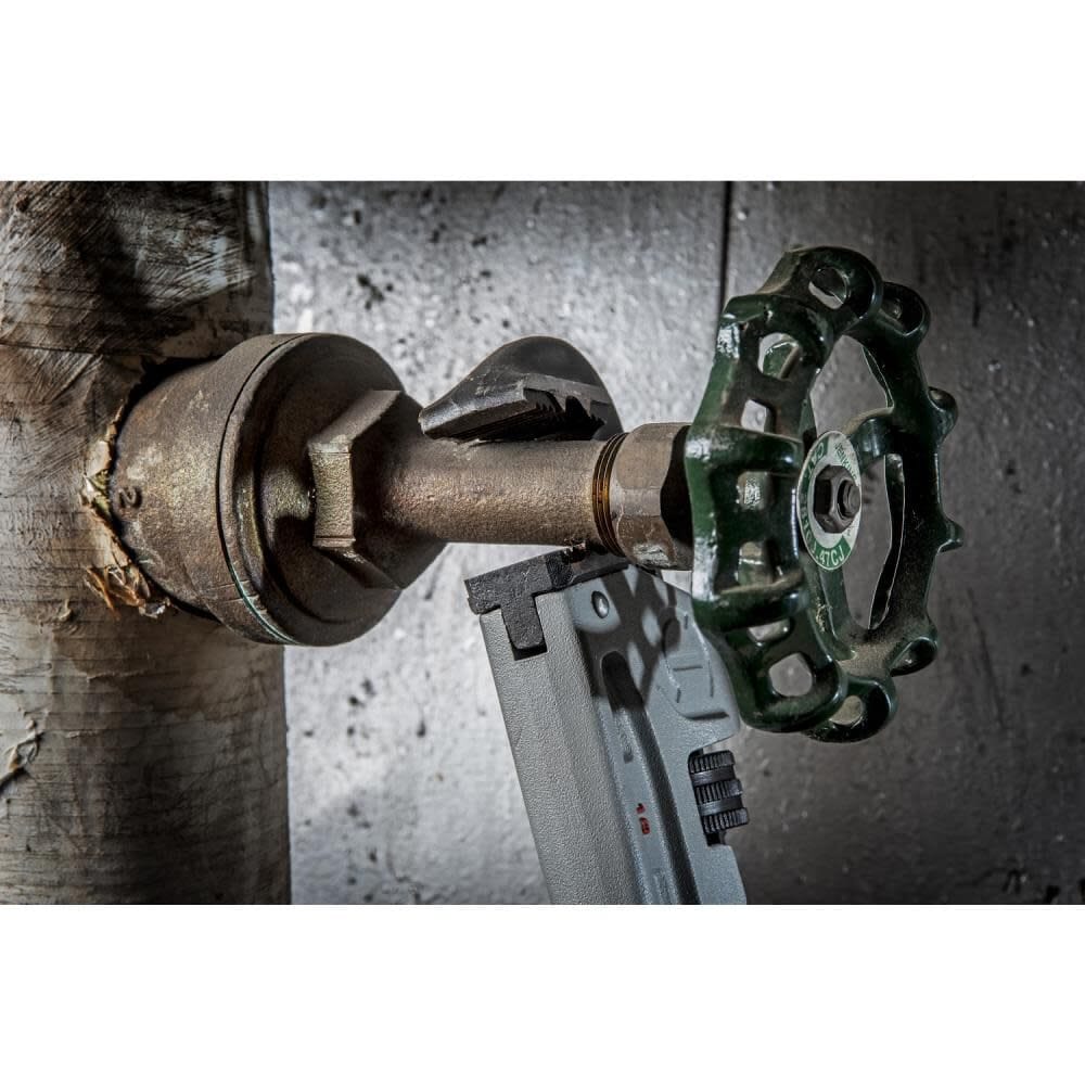 Close-up action shot of the Crescent 18-inch aluminum pipe wrench gripping a heavily rusted iron pipe fitting in a confined maintenance area.