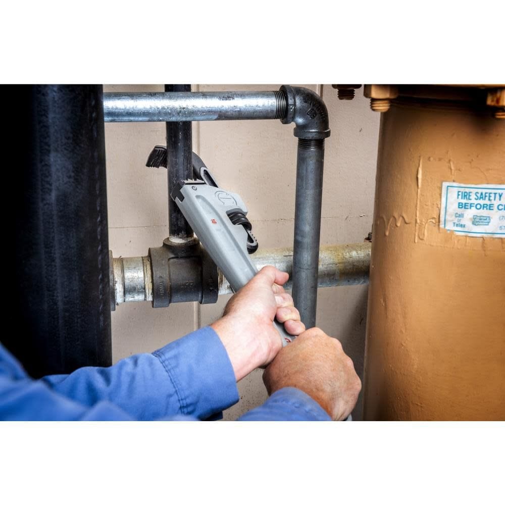 A worker using the Crescent 18-inch aluminum pipe wrench to tighten a high-pressure pipe fitting, demonstrating the tool's reach and leverage in industrial MRO settings.