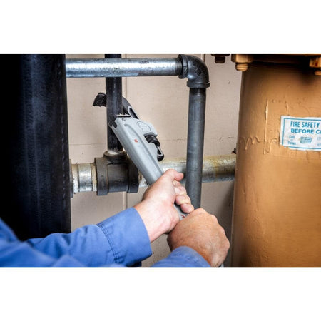 A worker using the Crescent 18-inch aluminum pipe wrench to tighten a high-pressure pipe fitting, demonstrating the tool's reach and leverage in industrial MRO settings.
