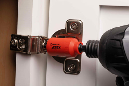 Close-up action shot demonstrating the Crescent u-GUARD non-marring bit holder safely fastening a metal hinge onto a white painted cabinet door without scratching the delicate surface.