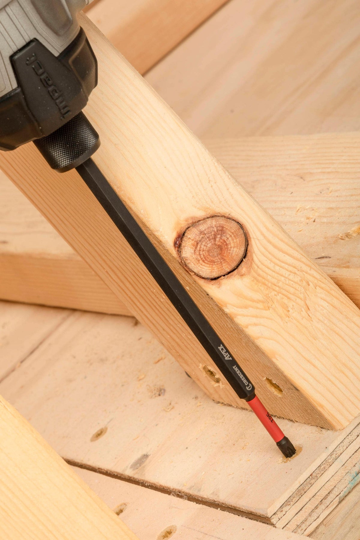 Crescent VORTEX Torx T25 6 inch screwdriver bit shown from a high angle action perspective inside a cordless impact driver chuck as it seats a wood screw flush into a structural timber rafter assembly to highlight walking-free fastener retention and professional jobsite durability.
