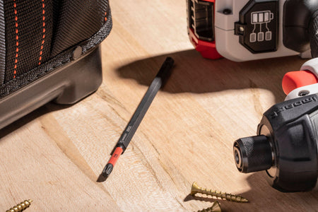 Crescent VORTEX heavy duty S2 alloy steel impact bit resting horizontally on a light wood workbench surface next to uninstalled star drive screws, a fabric open tool tote bag, and a cordless power tool battery pack base to illustrate trade professional jobsite readiness.