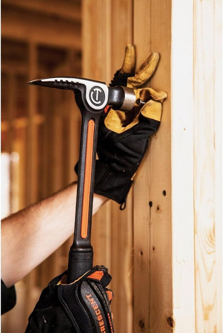 Action shot showing a professional using the Crescent CHSFRM22 framing hammer to start a nail into a wooden wall stud using the integrated magnetic nail starter.