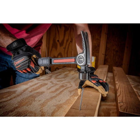 An action photograph showing a professional using the Crescent 20 oz steel hammer to drive a nail into a wooden beam, illustrating the precision balance and reduced vibration of the Vibeguard technology.