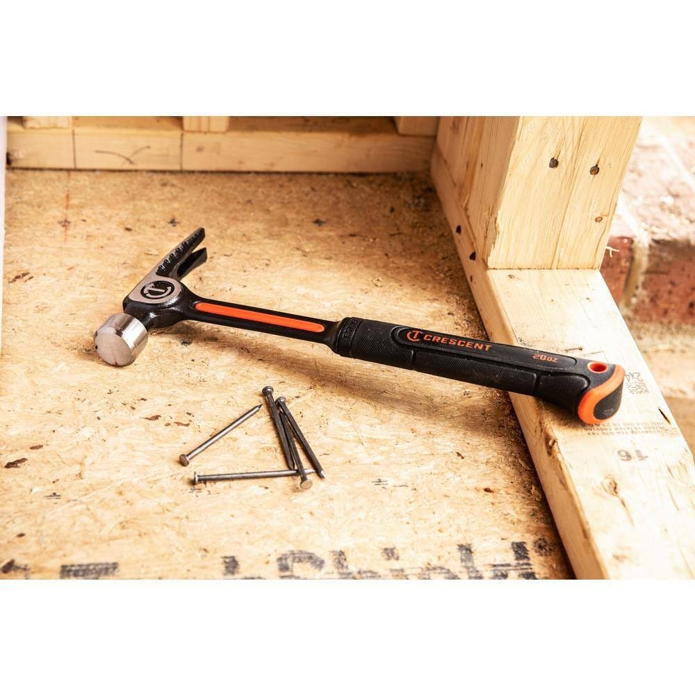 A lifestyle shot of the Crescent CHSGP20 general purpose hammer resting on a plywood subfloor next to several loose nails, highlighting its rugged build and readiness for residential construction projects.