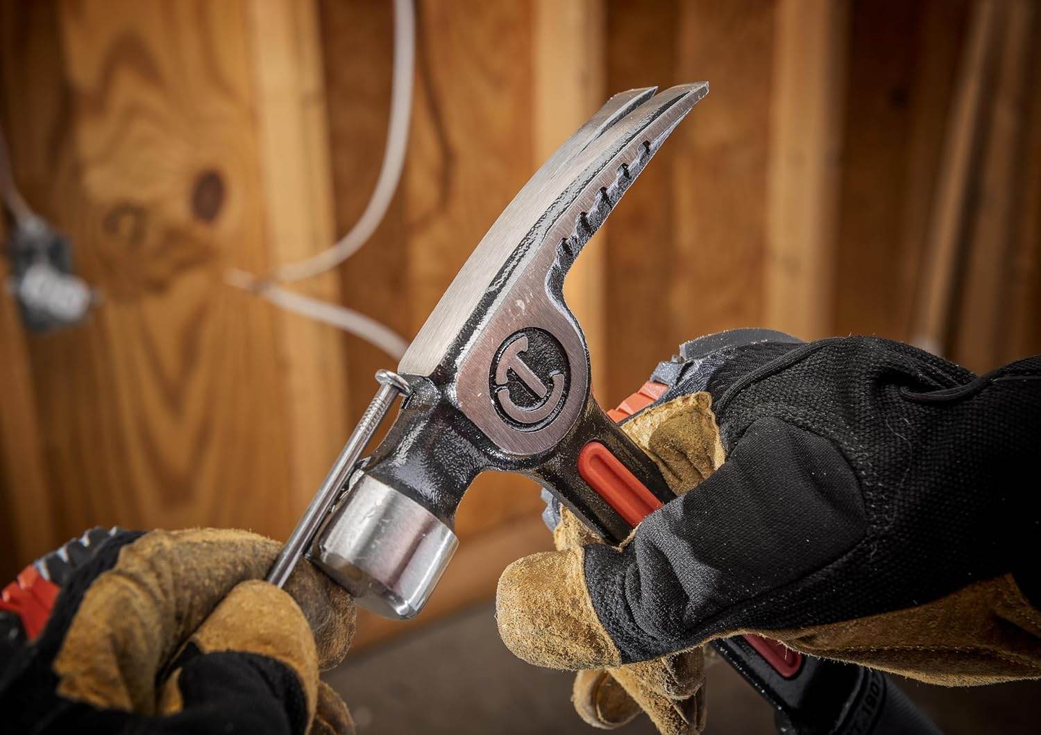 An action photograph of a professional woodworker using the magnetic nail starter on the Crescent 20 oz hammer to set a nail into a wooden stud, demonstrating efficient one-handed jobsite operation.