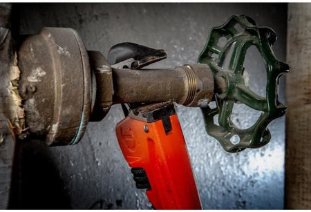Close-up detail of the Crescent 14-inch cast iron wrench head engaged with a metal fitting, highlighting the precision-machined teeth and rawhide powder coating.