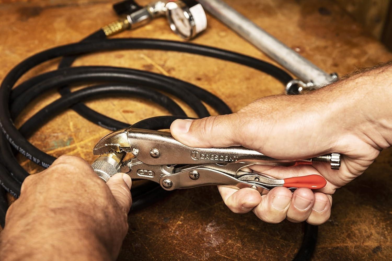 A professional worker uses the Crescent curved jaw locking pliers to provide a powerful, non-slip grip on a metal hydraulic hose fitting, illustrating the tool's performance in a real-world shop environment.